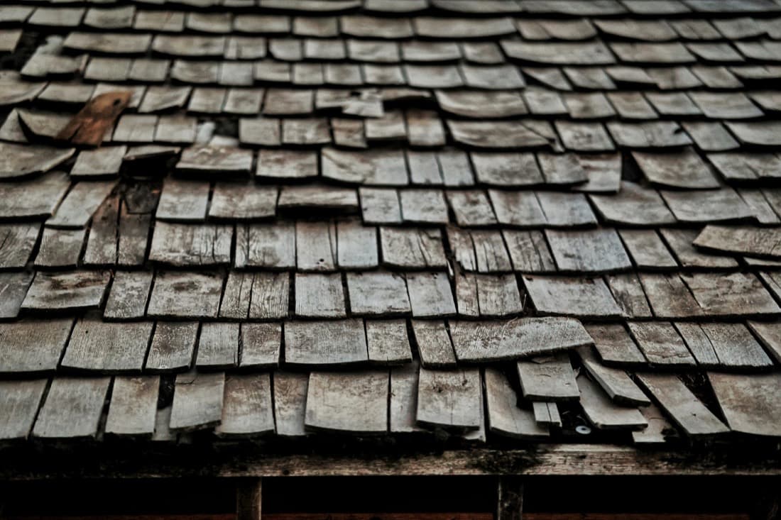 Aged wood-shingle roof with lifted and missing shingles